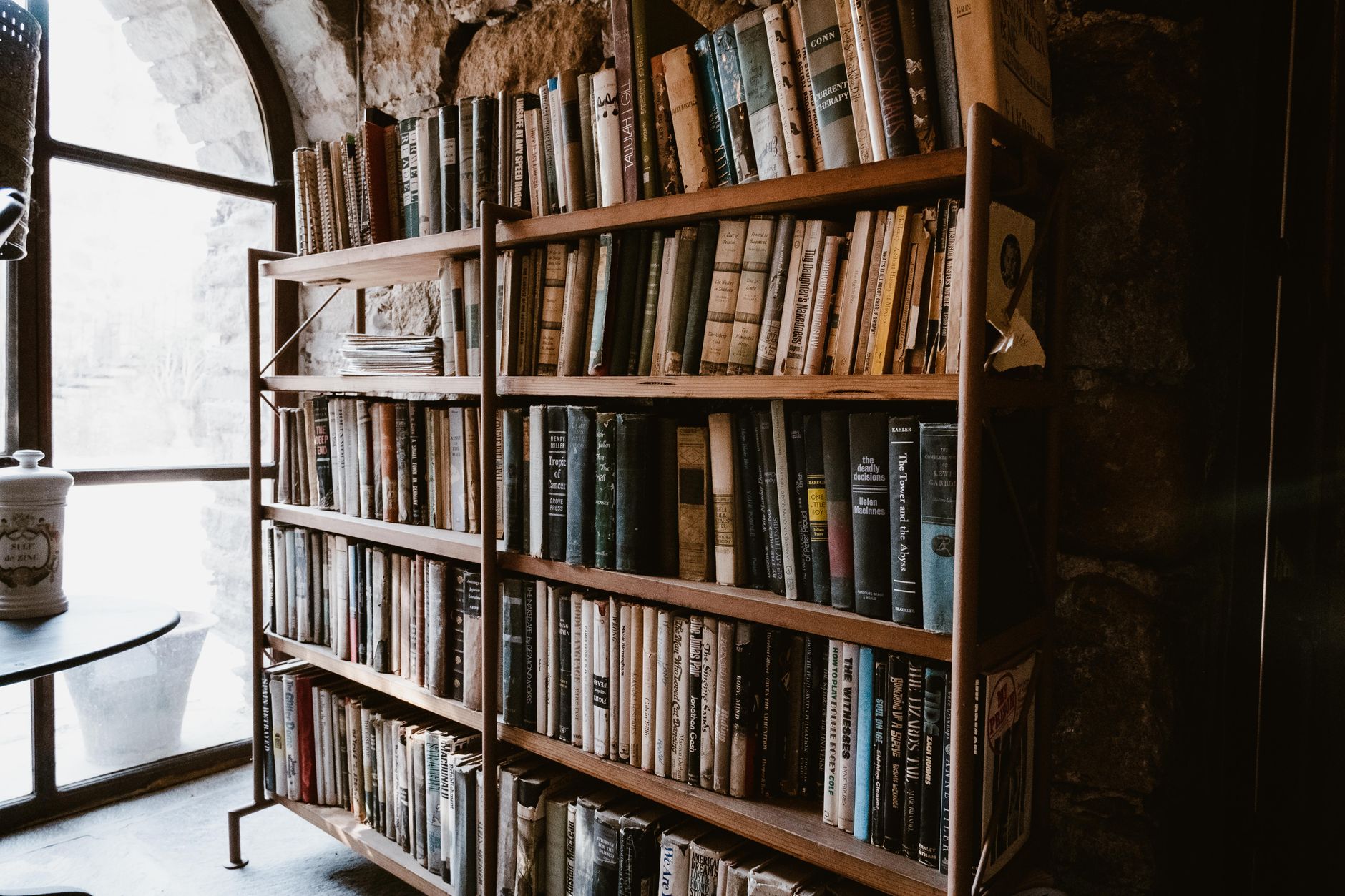 Une haute bibliothèque de bois chargée de livres anciens dans une pièce voûtée