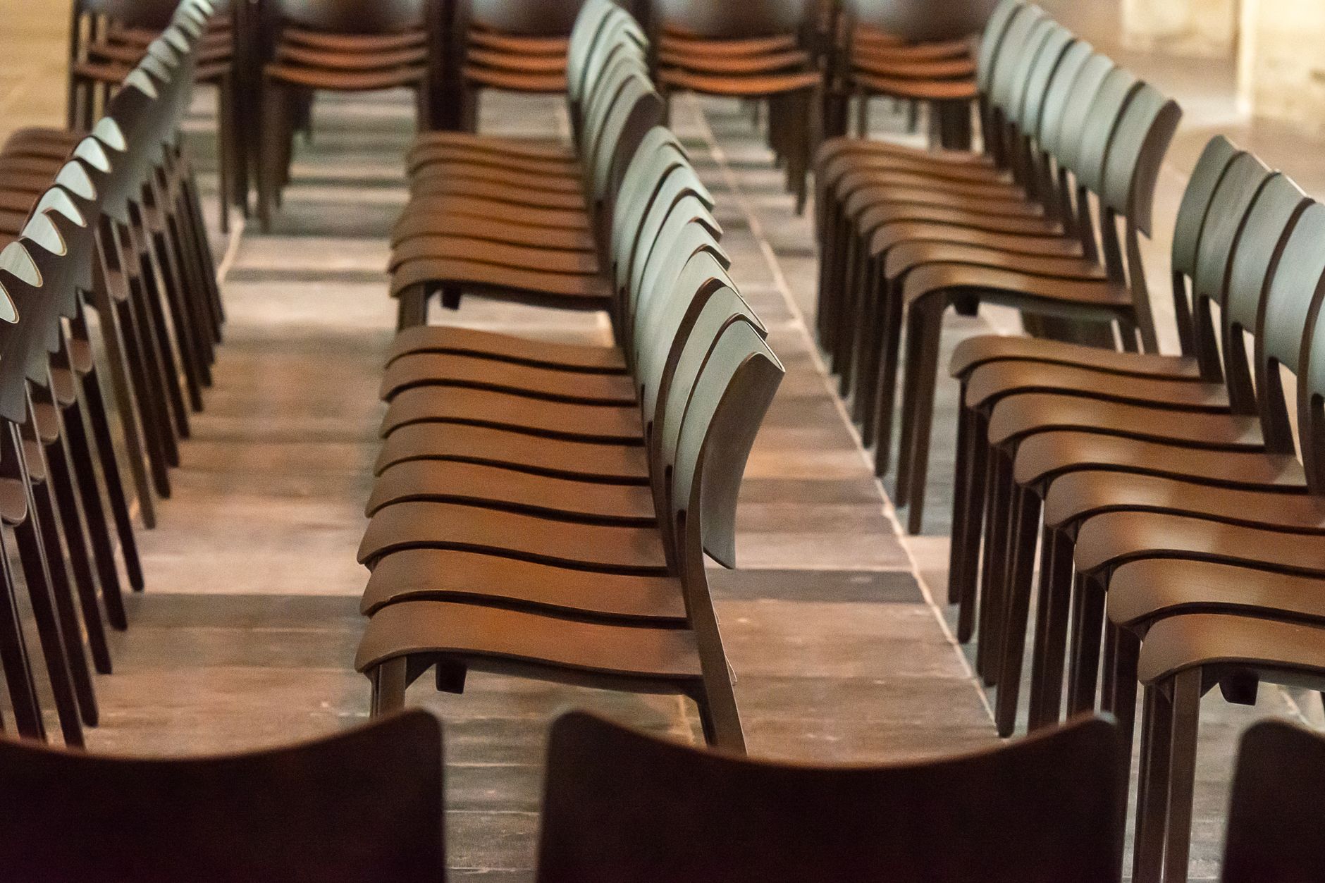 Des rangées de chaises de bois alignées dans une salle vide