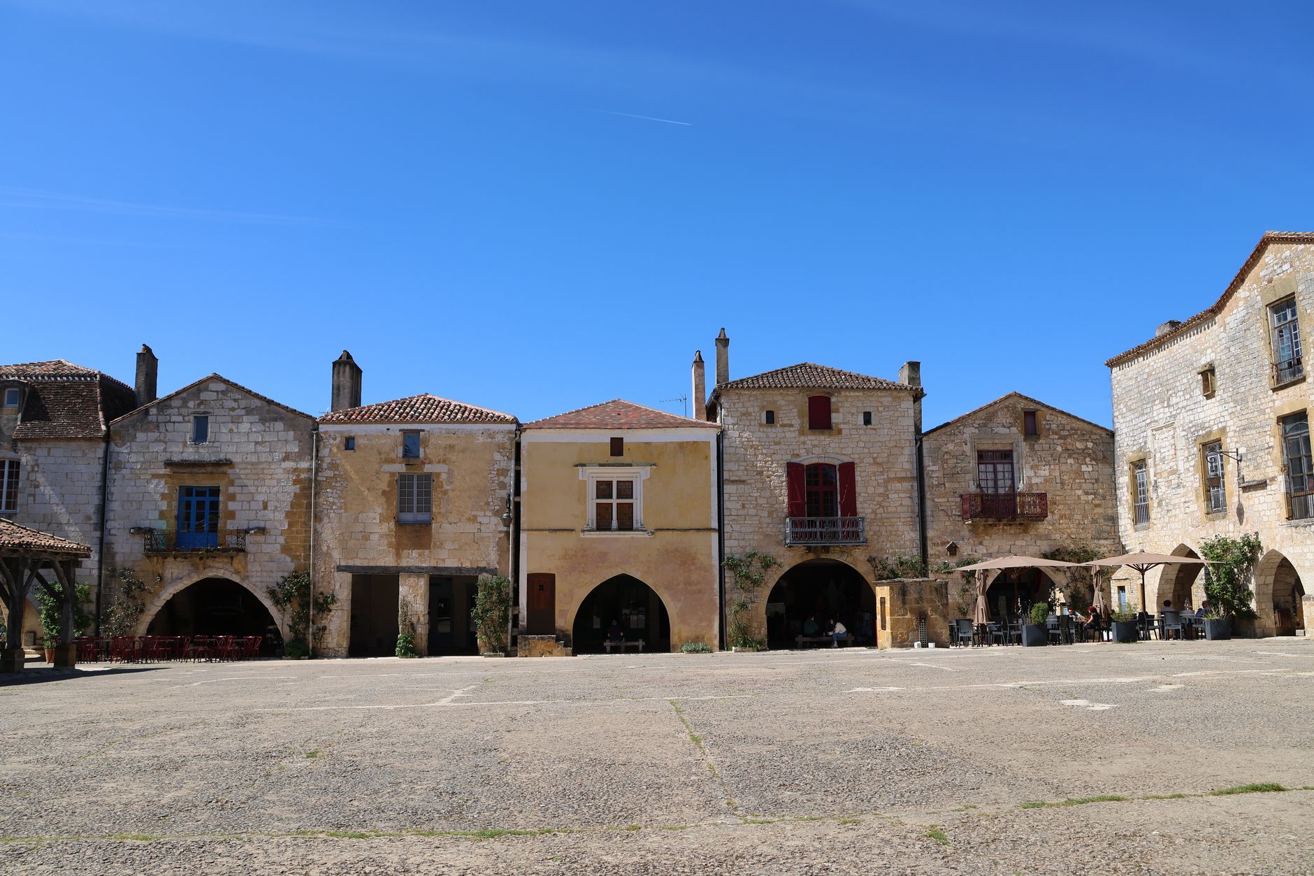 La place centrale d'un village français bordée de maisons de pierre à arcades
