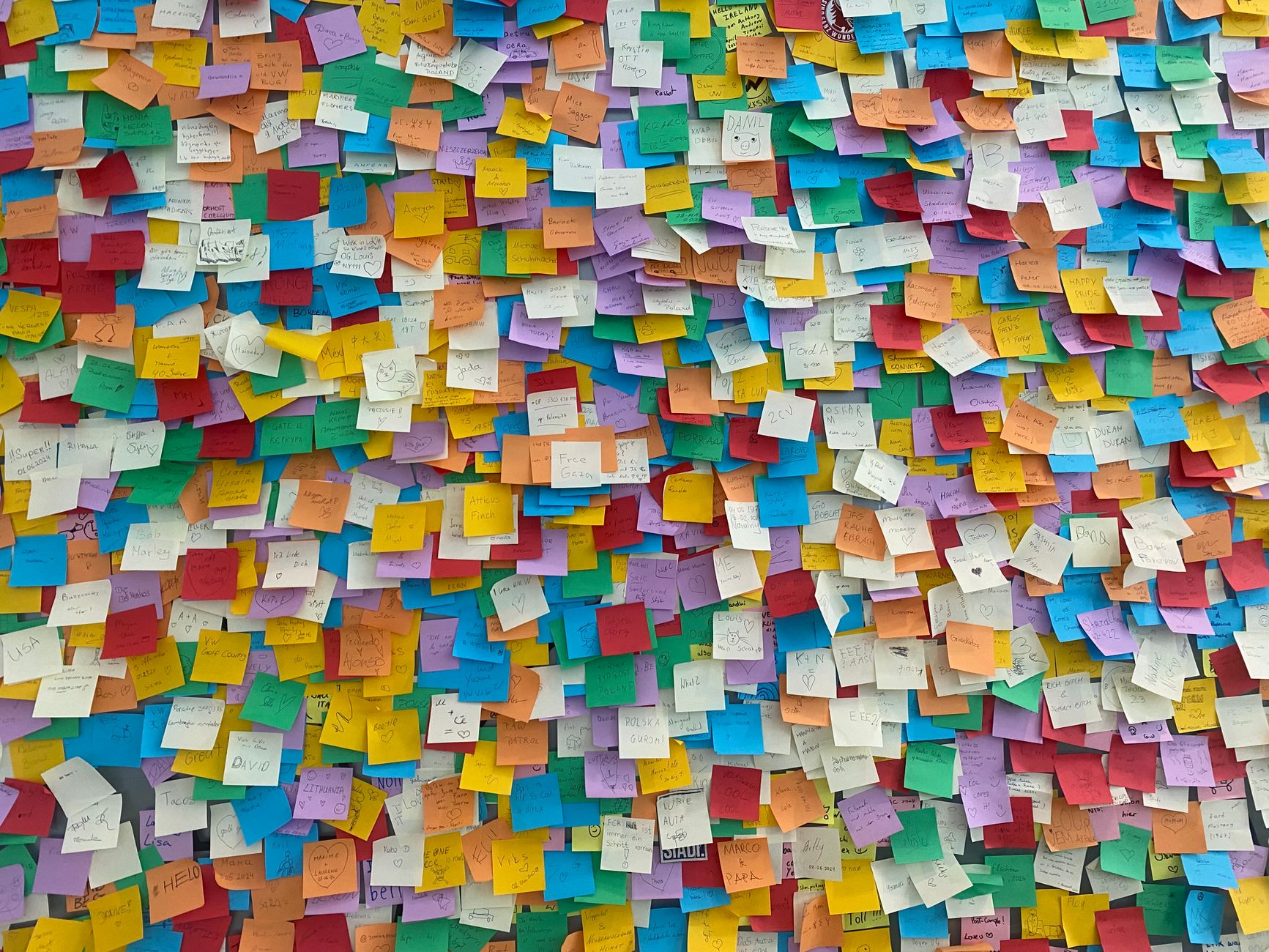 Un mur entièrement recouvert de petits papiers de couleur épinglés les uns à côté des autres